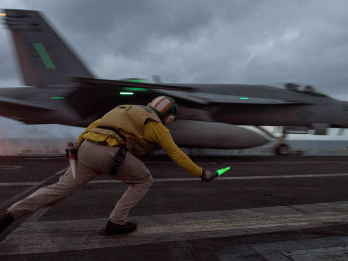 A sailor signals the launch of an F/A-18E Super Hornet from the flight deck of the USS Ronald Reagan on November 18.