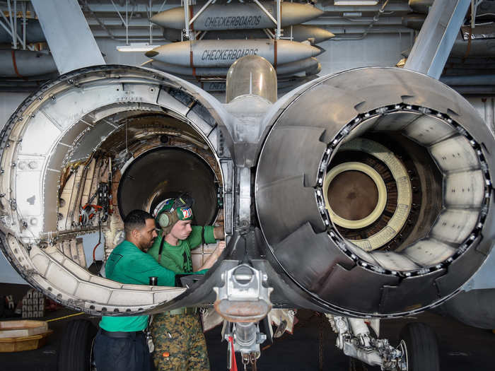 Airmen install a bleed air valve on an F/A-18C Hornet in the hangar bay of the USS Theodore Roosevelt on December 4.