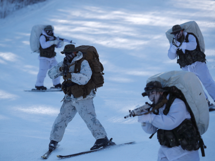 Here, a US Marine skis down a slope with three South Korean Marines