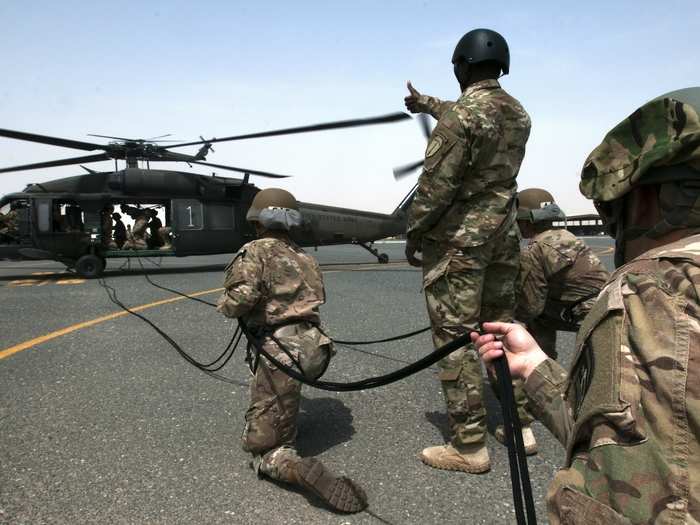 Air Assault recruits prepare to support their fellow students as they rappel from a UH-60 Blackhawk on April 13 at Camp Buehring in Kuwait.