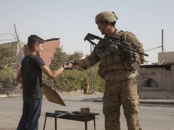 A Paratrooper, deployed in support of Combined Joint Task Force – Operation Inherent Resolve shakes the hand of a young boy in Mosul, Iraq, on July 4.