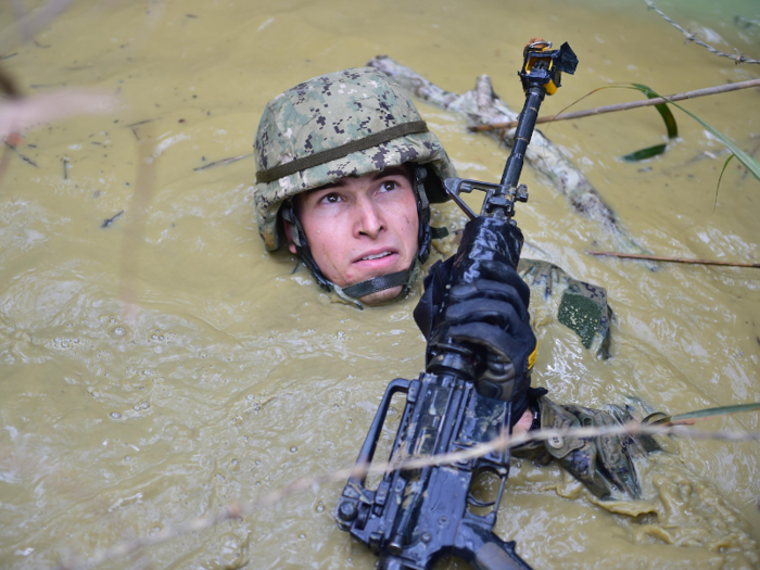 A member of the Naval Mobile Construction Battalion 5 traverses a mud-filled pit while participating in the endurance course at the Jungle Warfare Training Center in Okinawa, Japan, on February 17.