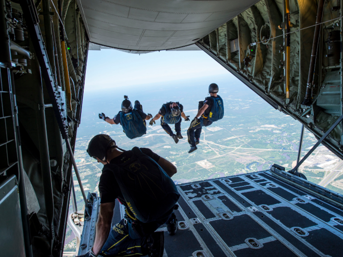 Members of the Leap Frogs, a US Navy parachute team, jump out of a C-130 Hercules during a skydiving demonstration above Biloxi High School in Mississippi on April 6.