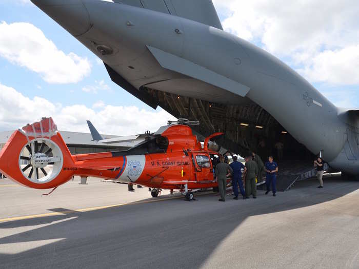 Coast Guard members offload MH-65 Dolphin helicopters from an Air Force C-17 aircraft at Coast Guard Air Station Miami in Opa Locka, Florida on September 11.