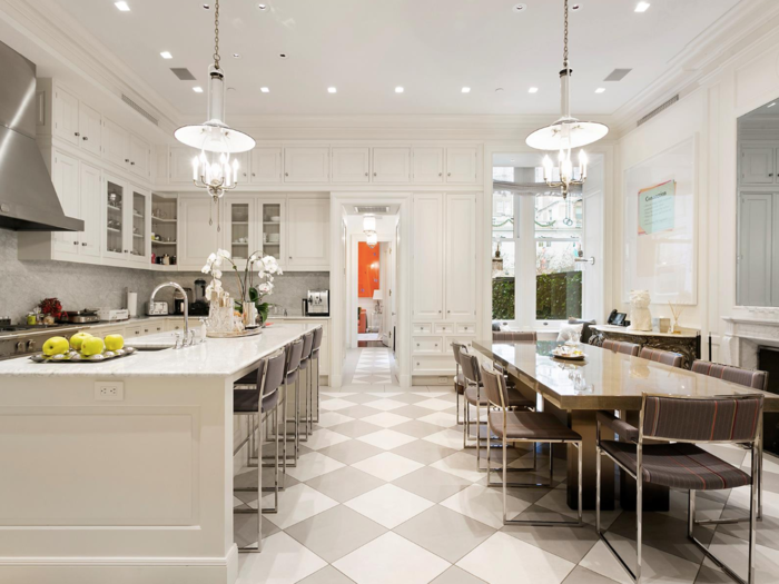 The spacious first-floor kitchen has sleek white cabinetry and countertops made with Carrara marble. There