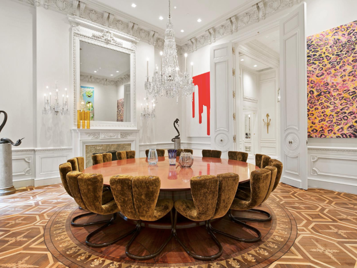 A second floor dining room with a marble fireplace and walls lined with art seats 14.