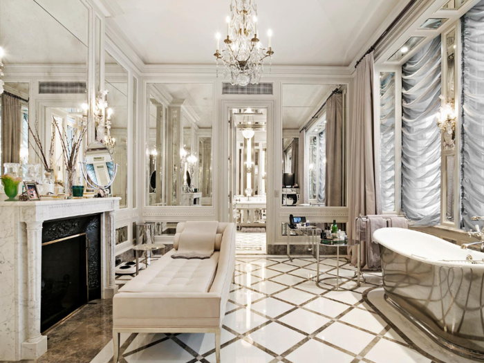 Attached is a decadent and mirror-lined master bathroom with a marble-framed fireplace.