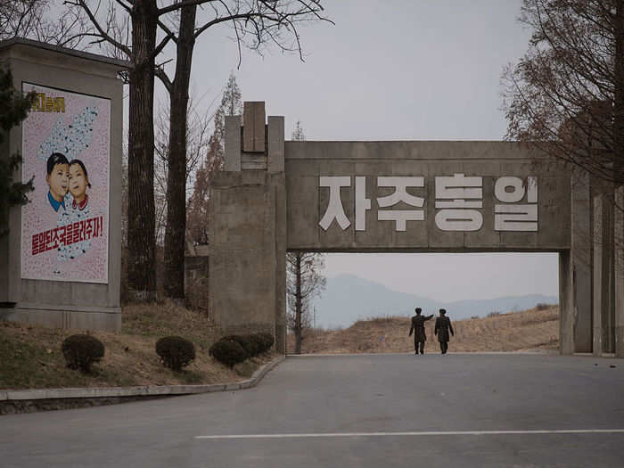 North Korean soldiers walk past a propaganda painting in Panmunjom.