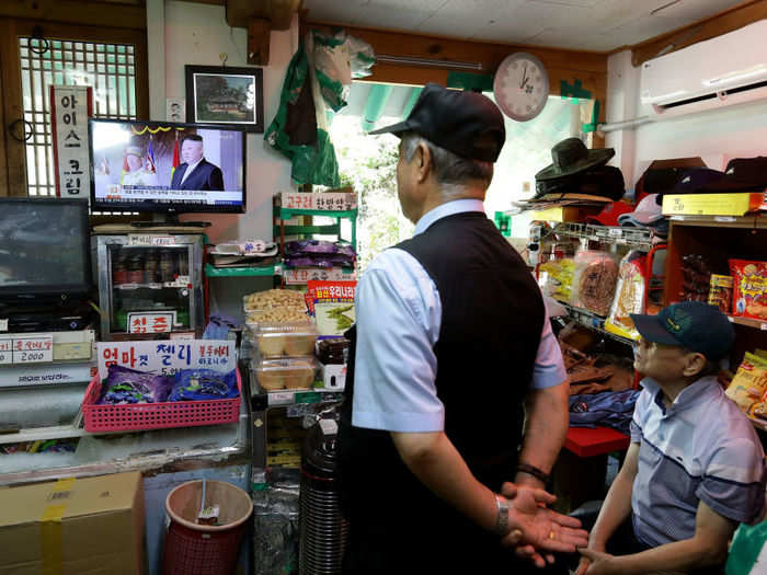 Nearby, South Koreans watch an announcement of a North Korean missile launch on TV inside a store.