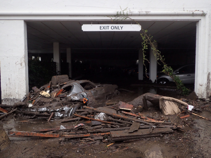 Debris flowed into car parks. The car on the left, covered in debris, is floating on a mixture of mud and water.