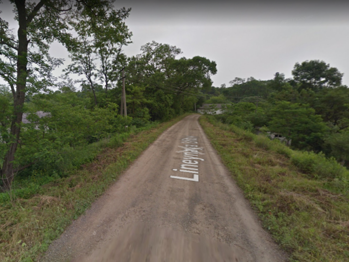 Beyond the gate is a pretty deserted lane, with some greenery concealing a few houses.