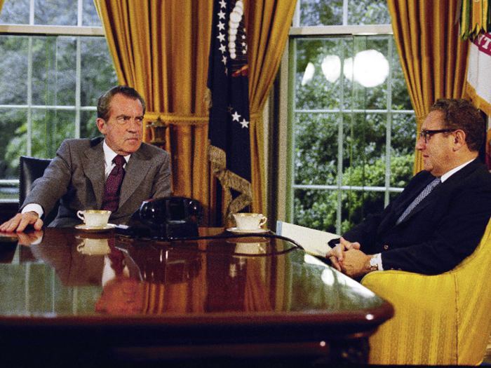 In this 1973 photo, Richard Nixon talks with Henry Kissinger over tea or coffee at his desk. On the table behind him, he kept a bust of Abraham Lincoln and family photos.