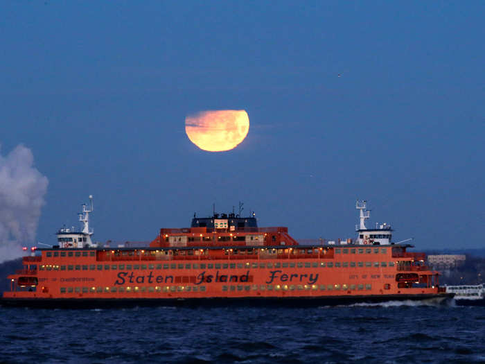 New Yorkers only got a partial view of the lunar eclipse, since the full effect occurred after sunrise on the US East Coast. Here the moon seen hovering over the Staten Island Ferry.