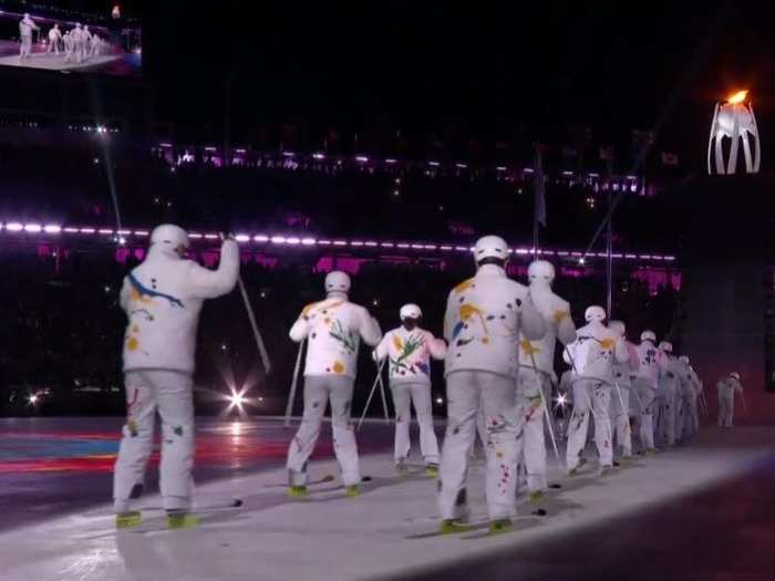 Dancers entered the stadium dressed for various Olympic events, such as cross-country skiing.