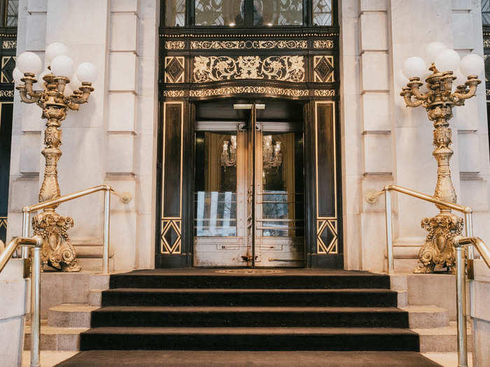 The entrance is wrought in golds, blacks, and whites. This is not the original entrance of the building — that is on Fifth Avenue. In 2008, the hotel reopened after a $400 million renovation that split the building into a 282-room hotel and 152 condominiums.