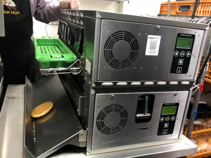 While one fast-food employee mans the grill, another worker has already put the buns in the toaster oven, where they are toasted golden brown in roughly 22 seconds.