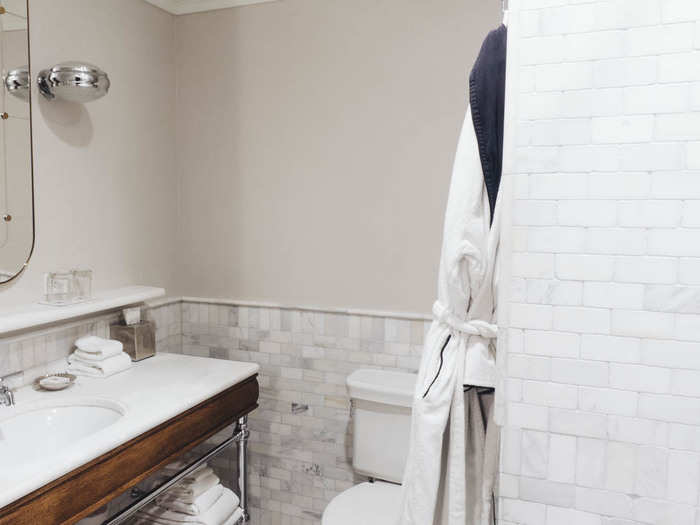 The bathroom is bright and modern looking, with marble covering most of the surfaces.