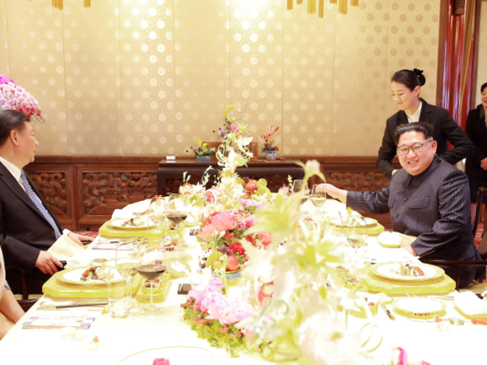 The Kim and Xi families also enjoyed a more intimate meal at some point. The server on the left appears to be holding a jug of orange juice.