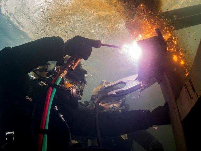 A US Navy equipment operator cuts a piece of steel in a training pool at South Korea