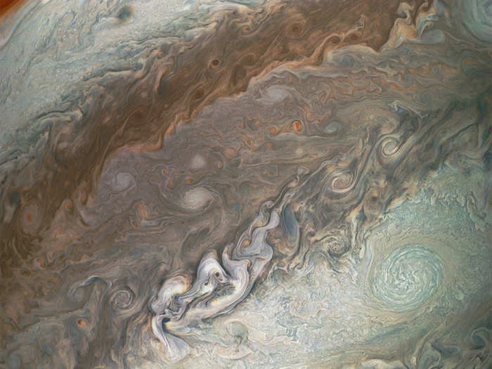 Smaller red storm cells are visible in a darker band near the Great Red Spot.