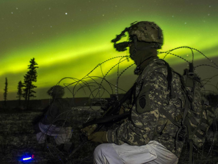 Soldiers secure an area in view of the aurora borealis during night live-fire training as part of Exercise Spartan Cerberus at Fort Greely, Alaska.