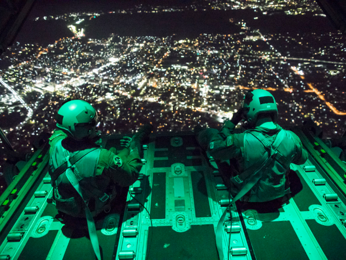 Senior Airman Stephen Clark and Airman 1st Class Matthew Pfeffer, 36th Airlift Squadron C-130J loadmasters, sit on the open ramp of a C-130J Super Hercules flying near Yokota Air Base, Japan.