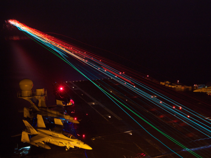 Aircraft land aboard the aircraft carrier USS Enterprise during nighttime flight operations in the Arabian Sea.