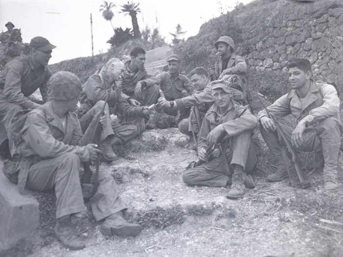 Pyle and some members of the 1st Marine Division rest by the roadside on Okinawa on April 8, 1945.