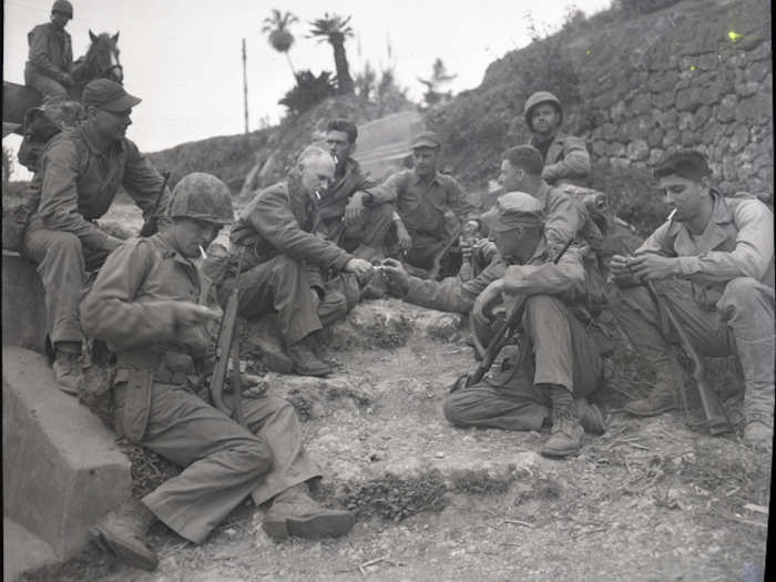 Pyle rests on the roadside with a Marine patrol on April 8, 1945.