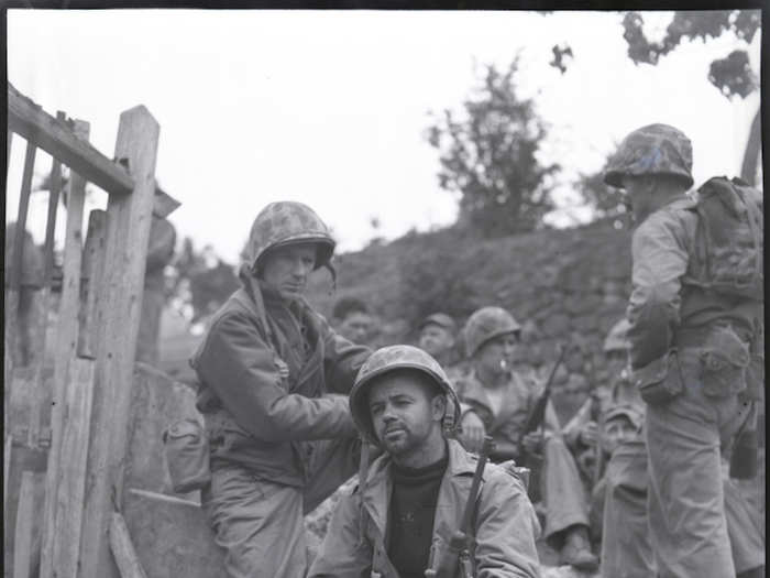 PFC. Urban Vachon and Pyle rest by the roadside on the trail at Okinawa on April 8, 1945.