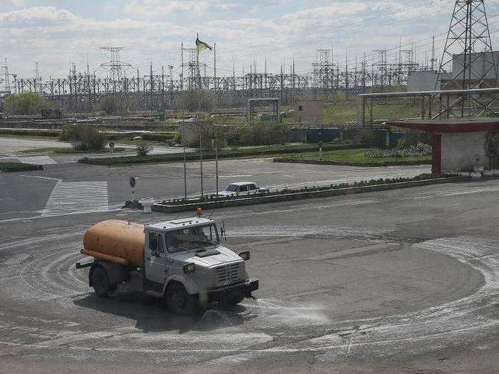 Outside, water tankers are used to spray water on a road to prevent radioactive dust from being blown away in front of the Chernobyl nuclear power plant.