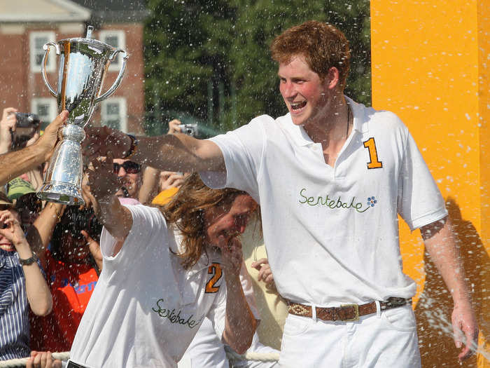 AGE 24: The Prince is sprayed with champagne by a Sentebale teammate after they triumphed over the Blackwatch team during the 2009 Verve Clicquot Manhattan Polo Classic on May 30, 2009 on Governor