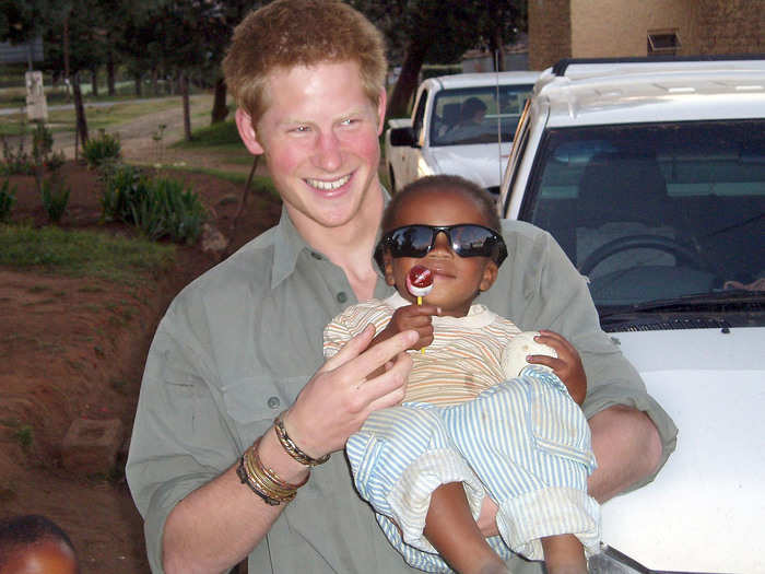 AGE 20: Prince Harry holds a child from one of the projects being helped by the Lesotho Fund, in Lesotho.