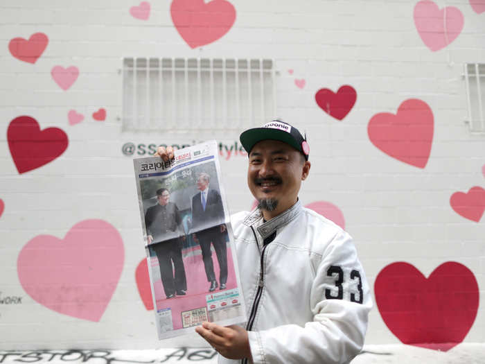 Ssoonie Kim, 45, poses in front of his beauty store with the front page of a newspaper with news of the meeting, Los Angeles, California, April 27, 2018.