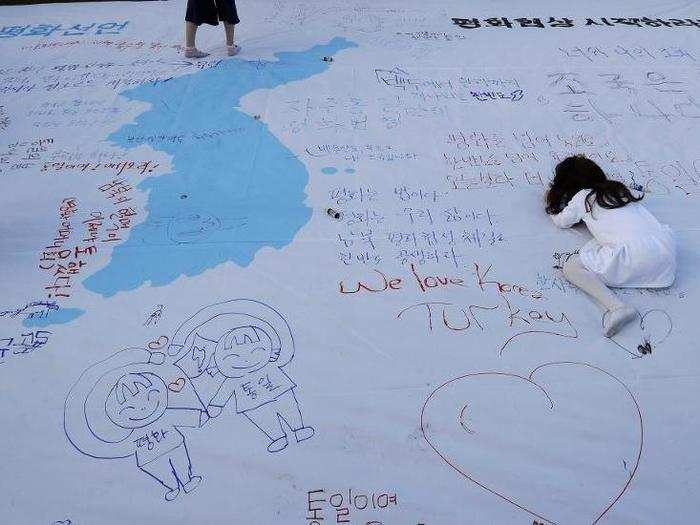 A woman writes a message next to a map of the Korean Peninsula during a welcoming event in downtown Seoul, South Korea, April 21, 2018.