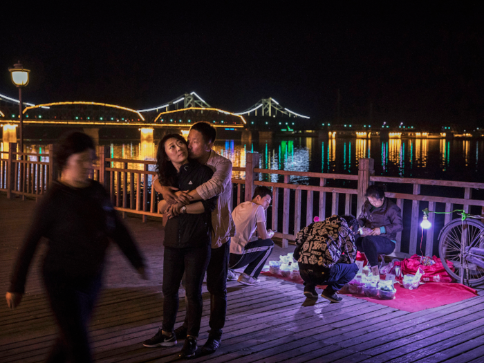 And as night falls, residents hang out on the boardwalk against the lit-up Friendship Bridge. Across the river, Sinuiju is completely dark.