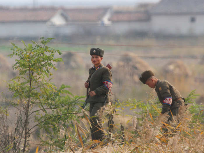 North Korea also installs military personnel to keep watch over its borders. These soldiers are patrolling the embankment on Hwanggumpyong Island in the middle of the Yalu River.