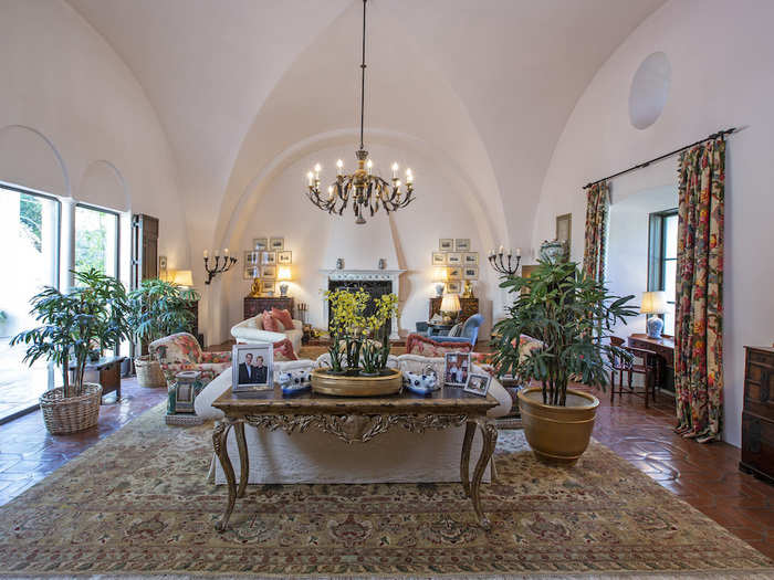 The living room has coved ceilings, a chandelier, and an oversized fireplace...