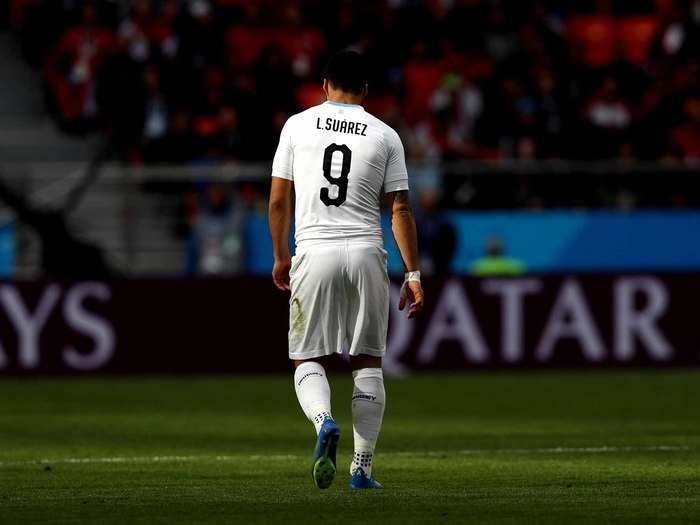 Luis Suarez walks across the pitch.