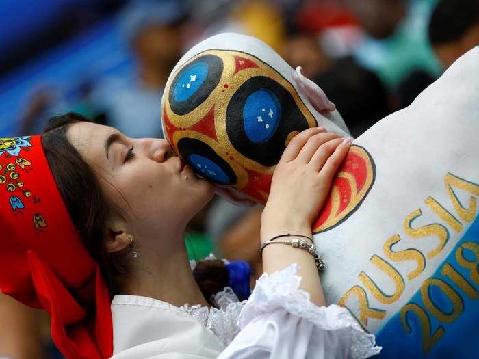 A fan kisses the World Cup logo on the back of another fan