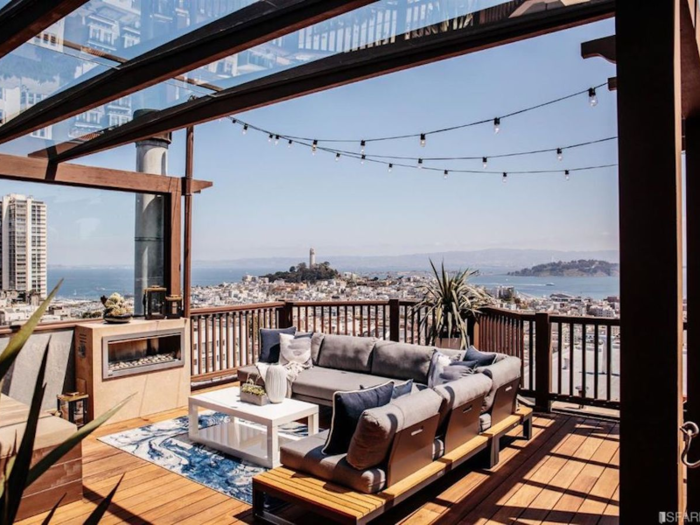 A pergola, and strings of large bulbed lights, hang in a canopy above one of the lounge areas of another deck.