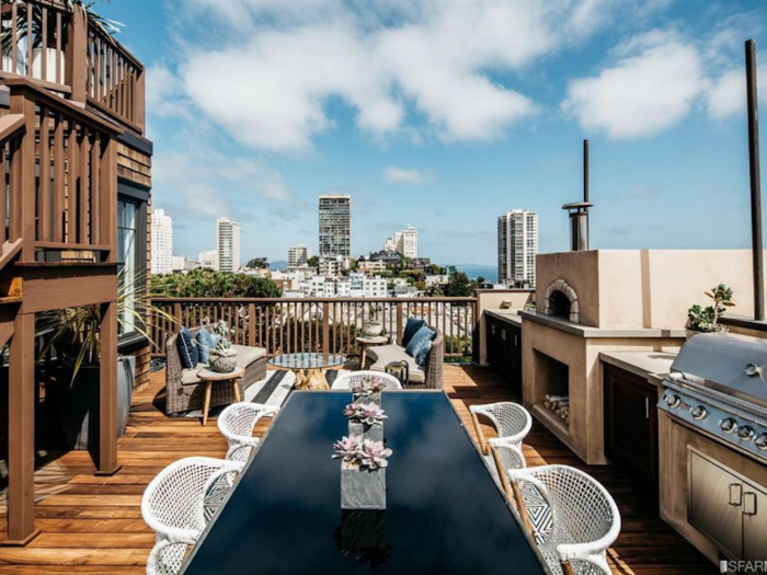 One of the outdoor decks features a dining table, a lounge area, a grill, and a fireplace.