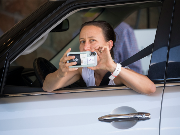 Anne Wojcicki, co-founder and chief executive officer of 23andMe, snaps a photo in return as she arrives at the conference.