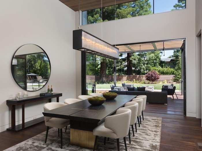 A large opening leading outside separates an indoor dining table and an outdoor seating area.