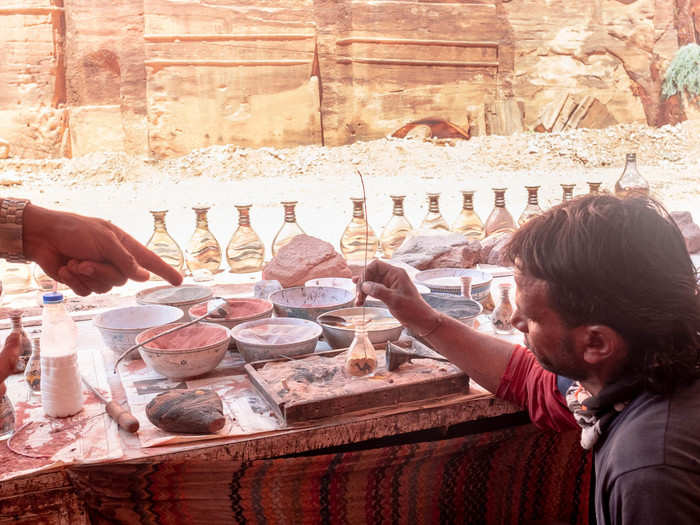 Members of the Bdoul tribe have set up stalls selling local handicrafts like this bottle of striated multicolored sands from the desert.