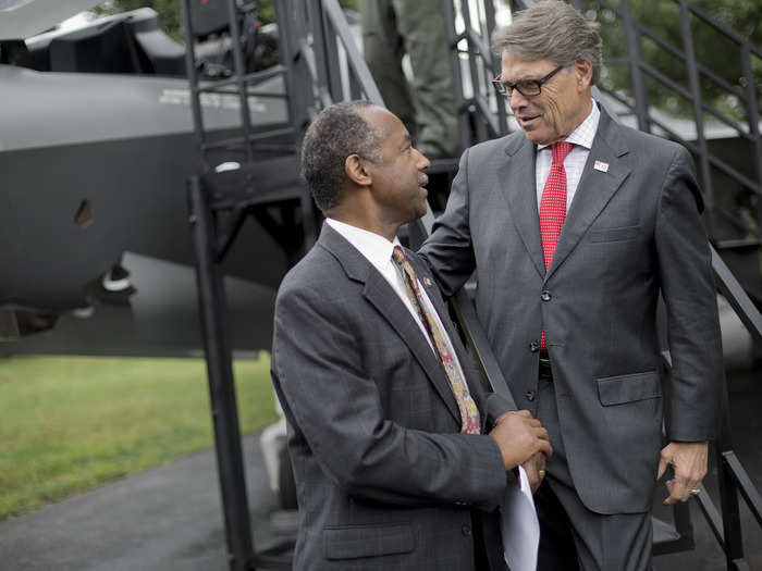 Housing and Urban Development Secretary Ben Carson, center, talks with Energy Secretary Rick Perry, right, after seeing the F-35.