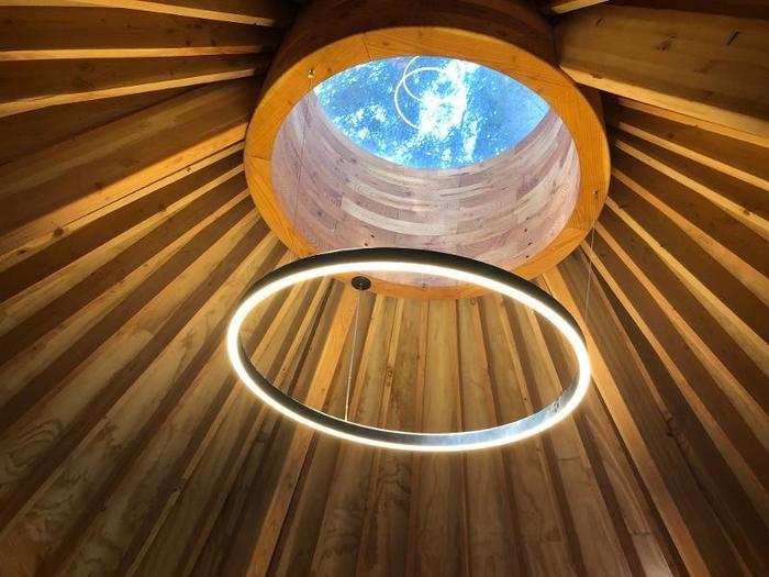 The treehouse is cone-shaped on the top, supported by wooden beams — but the main attraction is the skylight. You can even see the canopy of the trees, from the right angle.