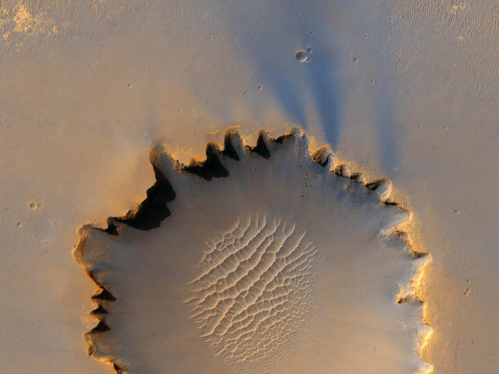 Near the Martian equator, the Victoria Crater at Meridiani Planum looks like abstract art. In this 2006 image captured by Orbiter, you can see the Opportunity rover as a tiny speck on the outside of the crater, between 9 and 10 p.m. if this were a clock.