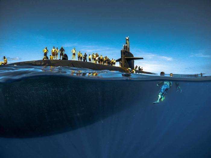 Sailors tread in the ocean next to their submarine, an attack boat based out of Pearl Harbor, Hawaii.