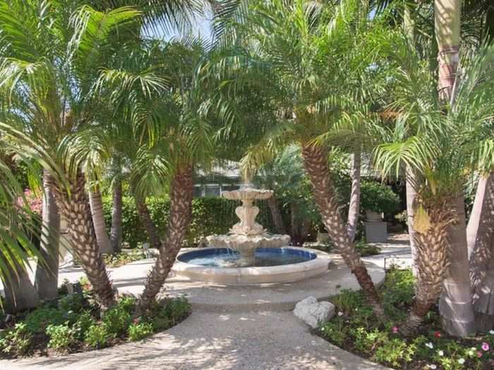 The exterior of the house has a courtyard with an elaborate fountain and palm trees.